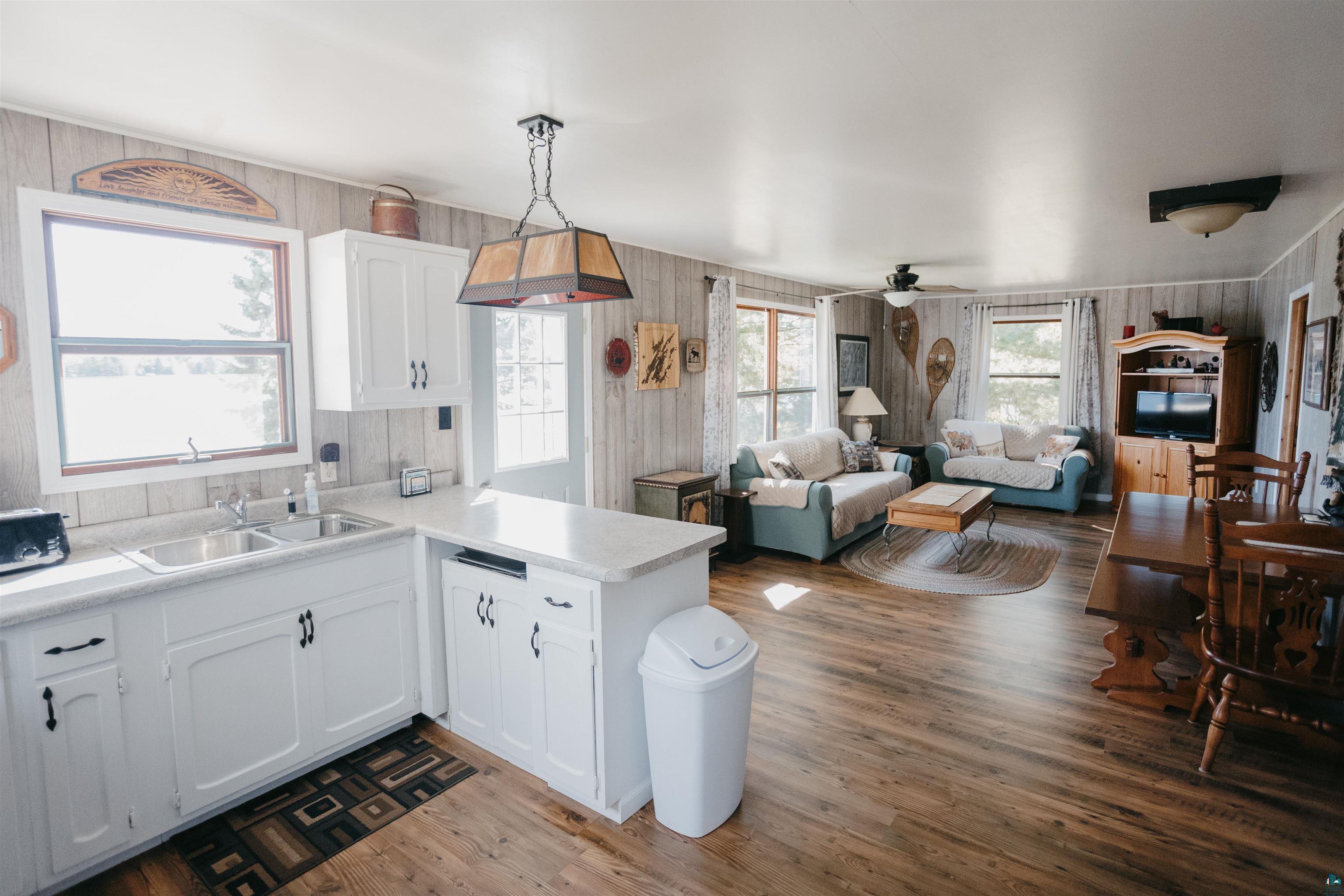 2308 South Weiberg Point Road Makinen, MN 55763 - Photo 11 of 33 Kitchen featuring pendant lighting, sink, white cabinets, wood walls, and kitchen peninsula