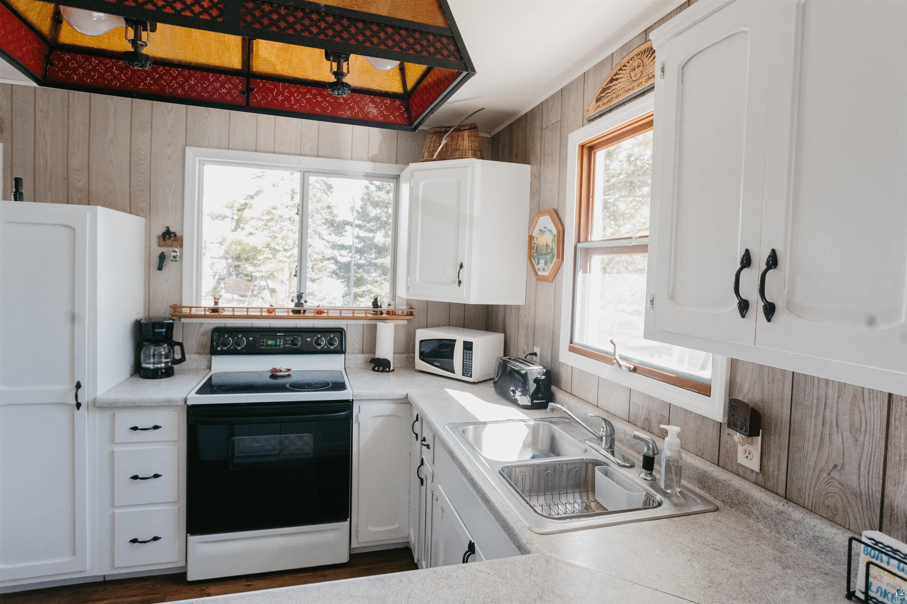 2308 South Weiberg Point Road Makinen, MN 55763 - Photo 12 of 33 Kitchen with white appliances, wooden walls, sink, and white cabinets