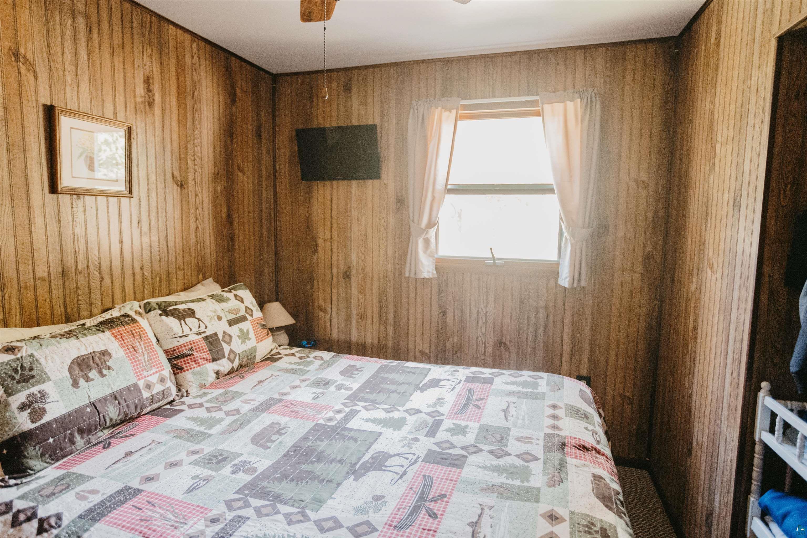 2308 South Weiberg Point Road Makinen, MN 55763 - Photo 16 of 33 Unfurnished bedroom with ceiling fan and wood walls