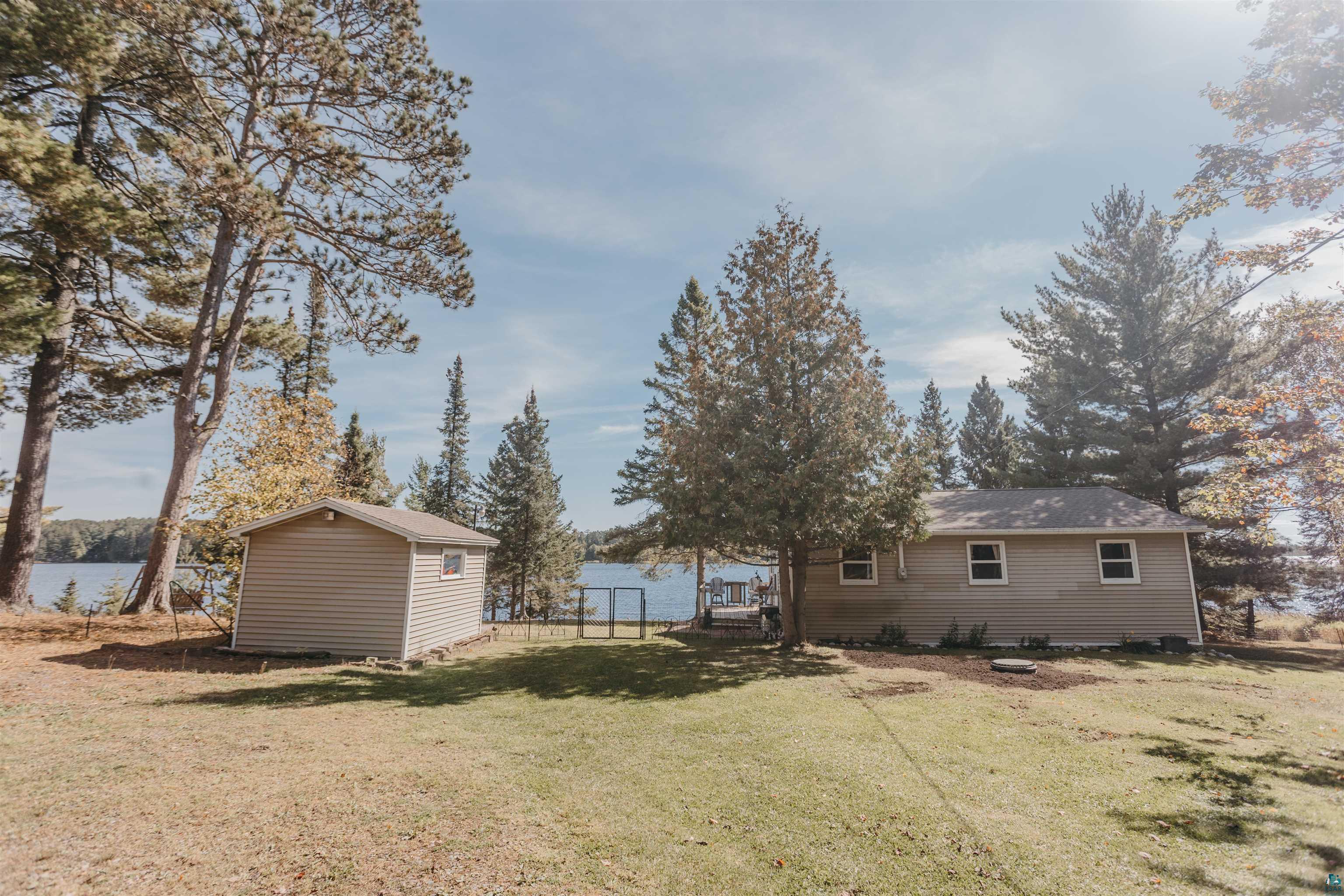 2308 South Weiberg Point Road Makinen, MN 55763 - Photo 32 of 33 Rear view of house with a storage shed, a lawn, and a water view
