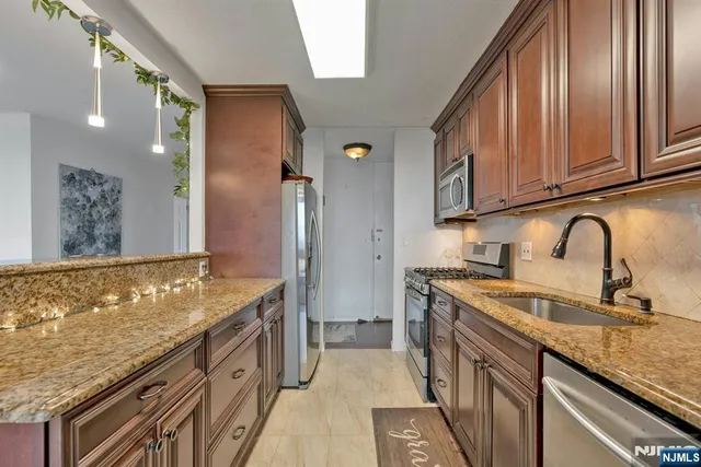 a kitchen with stainless steel appliances granite countertop a sink stove and refrigerator