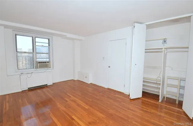 a view of empty room with wooden floor and window