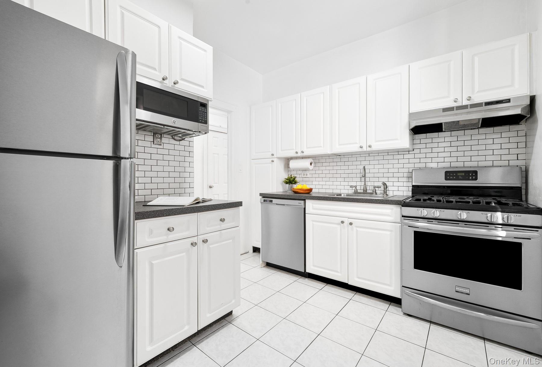 41-42 42nd Street, Unit E4 Queens, NY 11104 - Photo 6 of 17 a kitchen with granite countertop white cabinets and white appliances