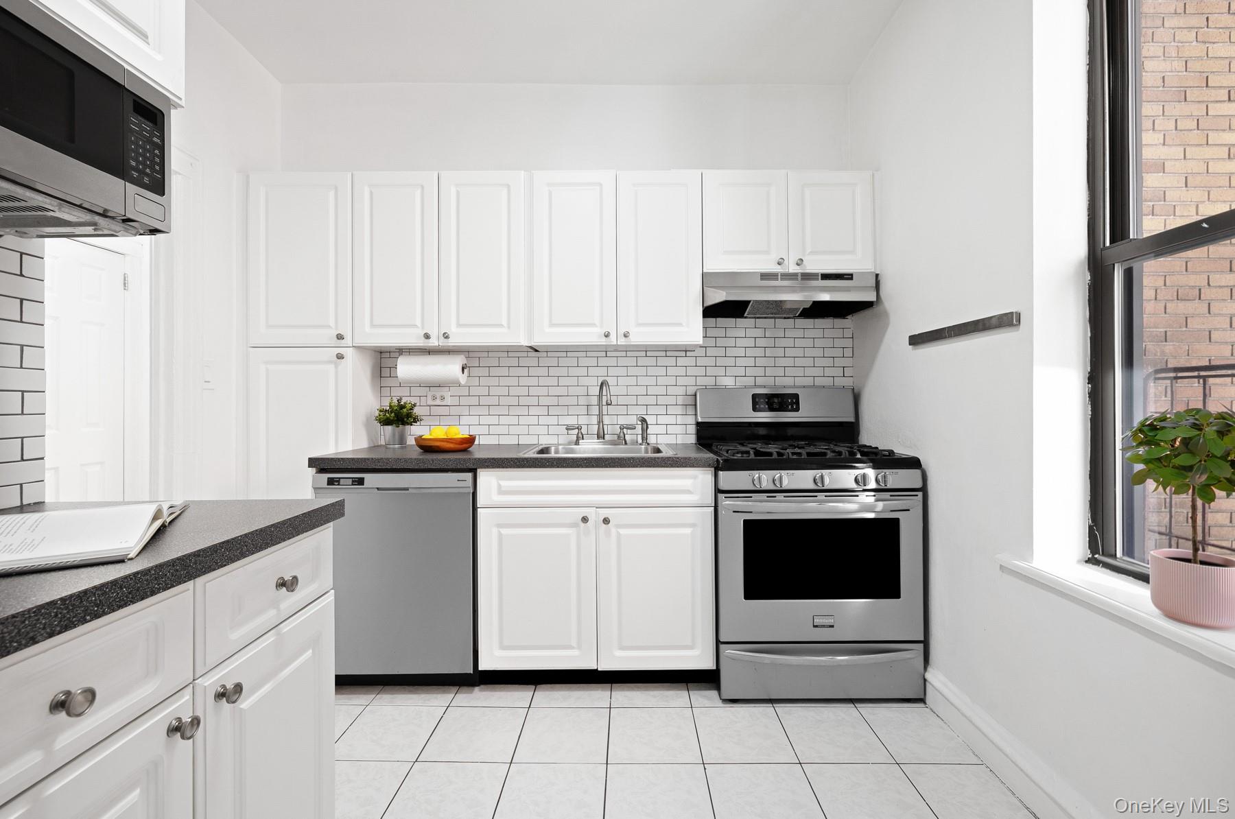 41-42 42nd Street, Unit E4 Queens, NY 11104 - Photo 7 of 17 a kitchen with granite countertop white cabinets and white appliances