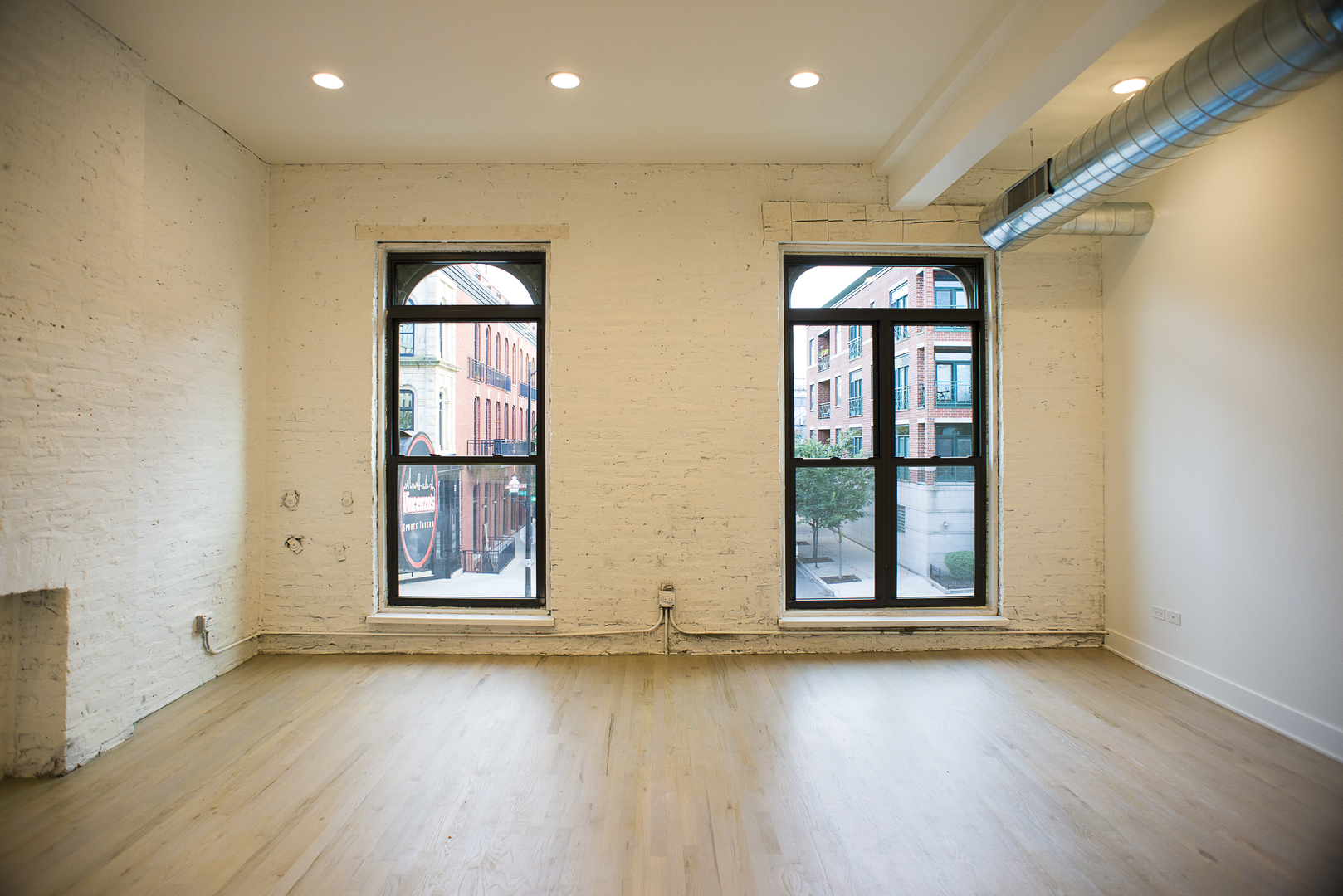 1104 West Madison Street, Unit 2S Chicago, IL 60607 - Photo 2 of 9 an empty room with wooden floor and windows