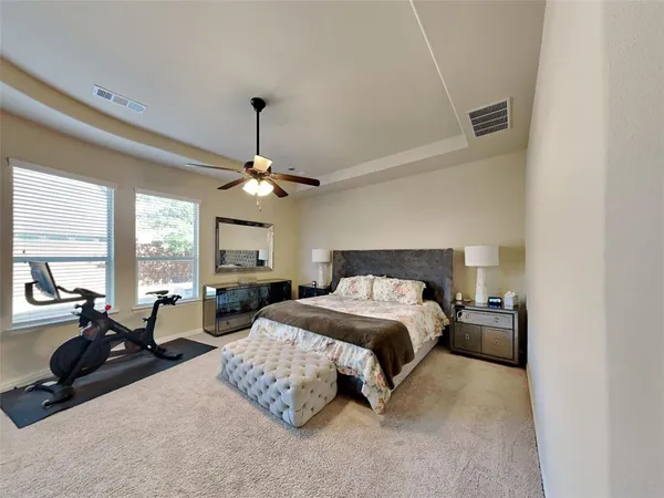 a spacious bedroom with a bed a chandelier and large windows