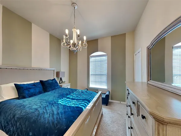 a spacious bedroom with a large bed and a chandelier