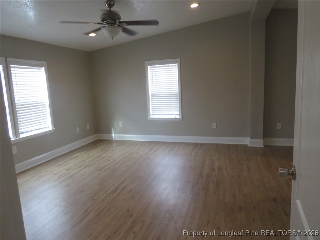 1184 Fisher Road St. Pauls, NC 28384 - Photo 13 of 29 an empty room with wooden floor chandelier fan and windows