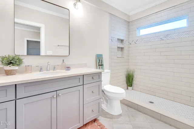 a bathroom with a sink a toilet a mirror and shower