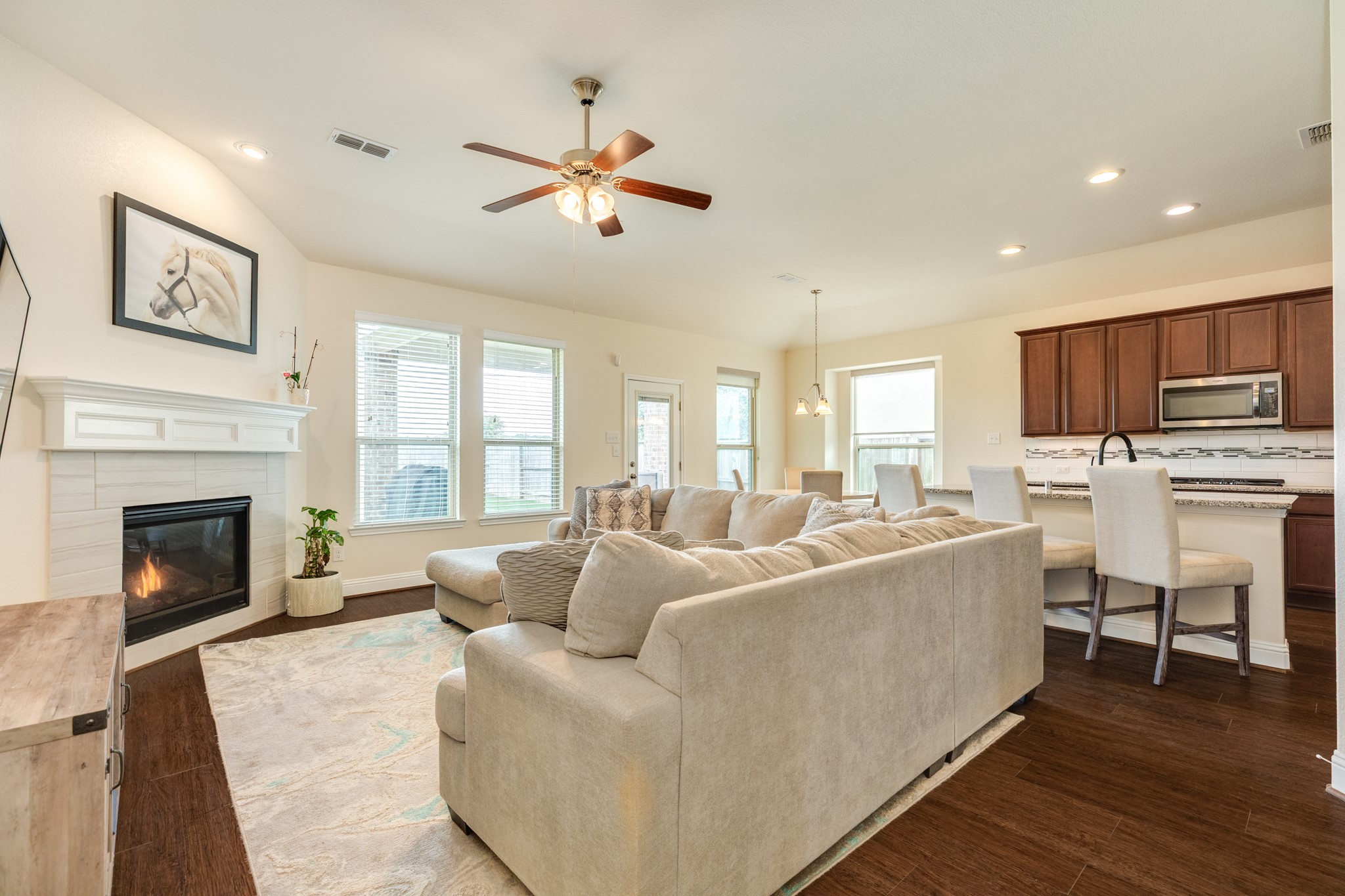 3519 Bay Drive Rosharon, TX 77583 - Photo 10 of 49 Spacious family room featuring abundant natural light from numerous windows overlooking the covered patio and backyard. The room is enhanced by recessed lighting and a cozy corner gas log fireplace, offering a perfect blend of comfort and style for relaxation or entertaining.