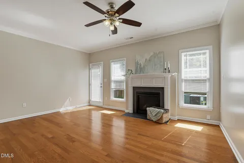 a view of a livingroom with a fireplace a ceiling fan and windows