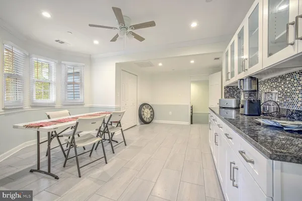 a dining hall with stainless steel appliances granite countertop a stove a sink a dining table and chairs with wooden floor