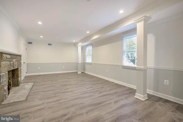 an empty room with wooden floor fireplace and windows