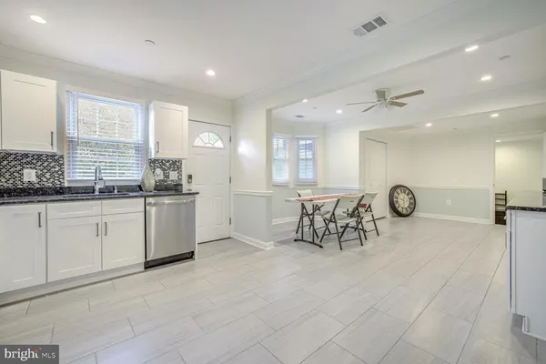 a large white kitchen with white cabinets and chandelier