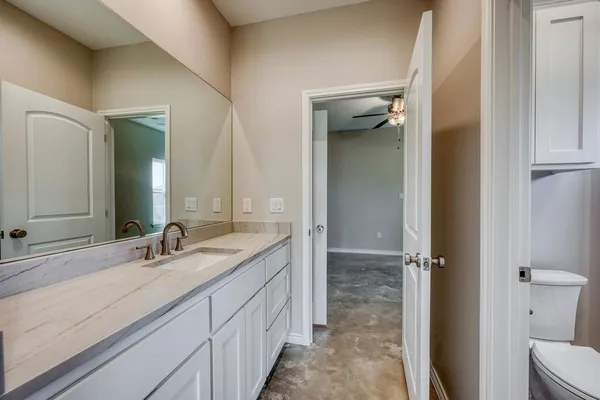 a bathroom with a double vanity sink and mirror with toilet