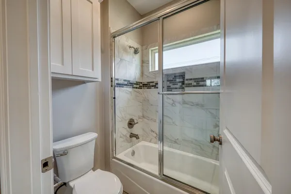 a bathroom with a granite countertop bathtub shower and toilet