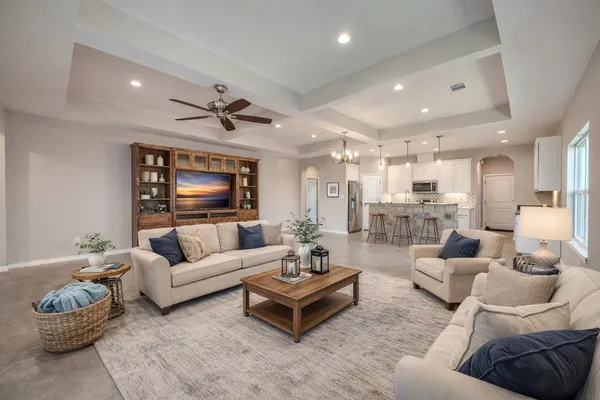 a living room with furniture kitchen view and a chandelier