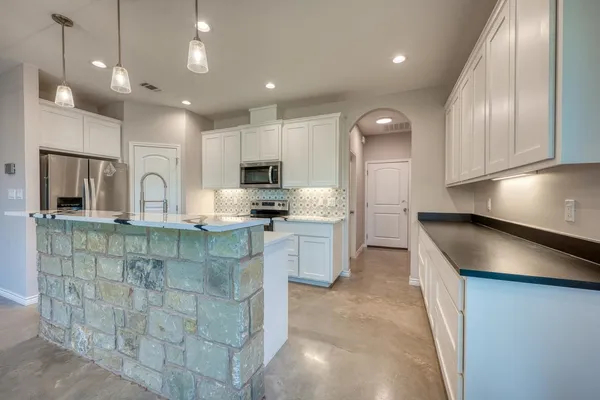 a kitchen with kitchen island granite countertop a sink cabinets and stainless steel appliances
