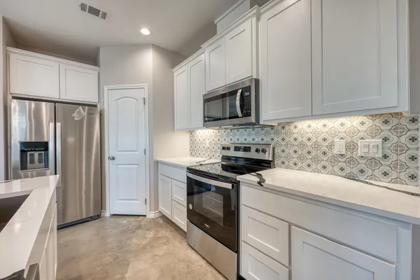 a kitchen with granite countertop white cabinets stainless steel appliances and a sink