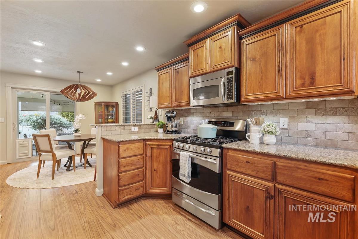 647 North Shadowfox Place Eagle, ID 83616 - Photo 12 of 35 Kitchen featuring a breakfast bar, stainless steel appliances, custom cabinets, granite counters