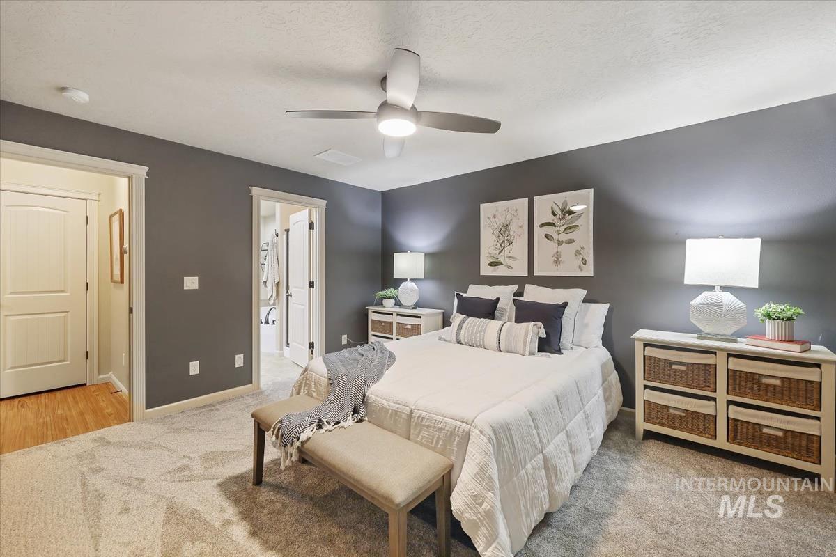 647 North Shadowfox Place Eagle, ID 83616 - Photo 15 of 35 Bedroom with new light-colored carpet, a ceiling fan, a textured ceiling, and ensuite bathroom