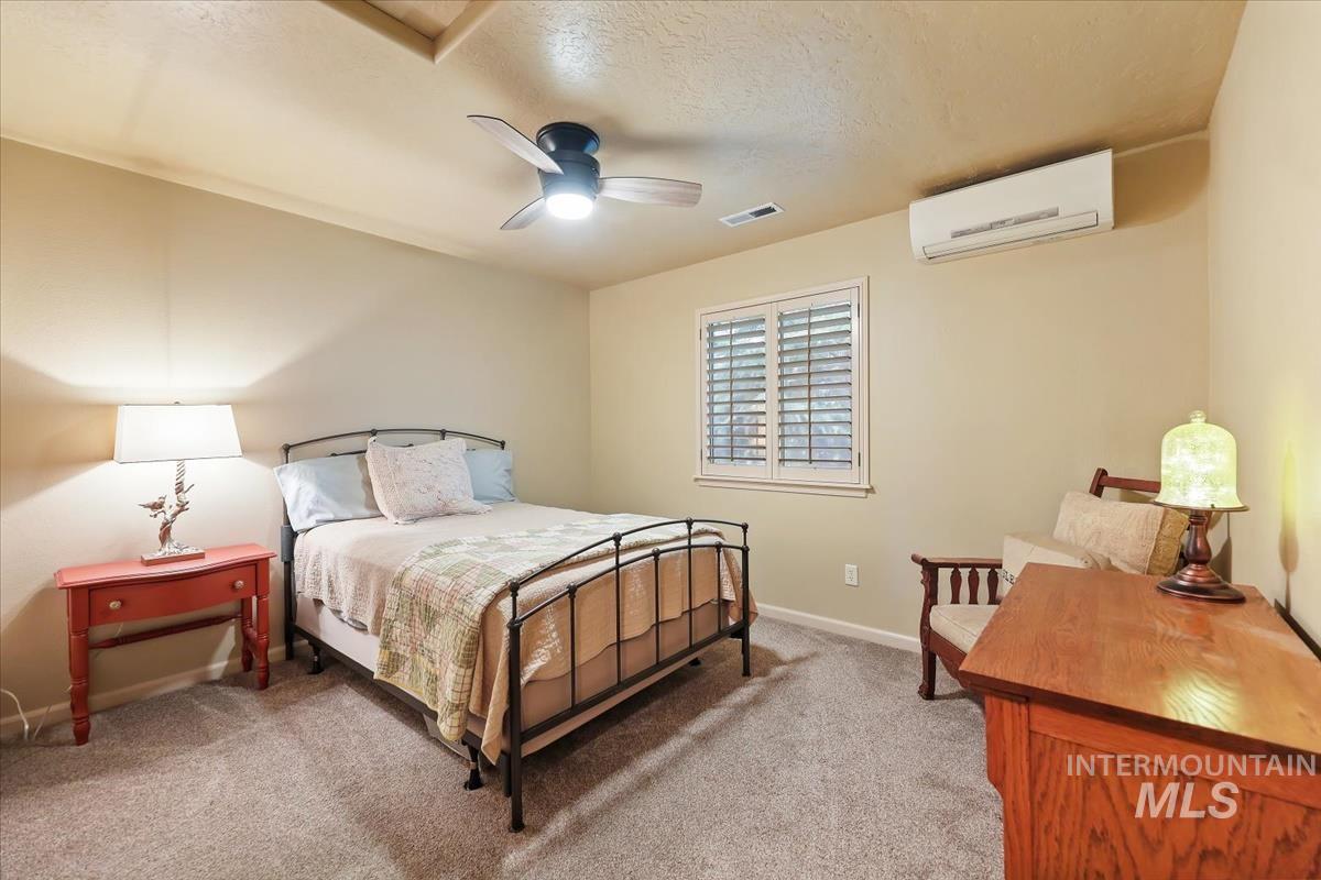 647 North Shadowfox Place Eagle, ID 83616 - Photo 30 of 35 Bedroom with a wall mounted AC, newer carpet, ceiling fan, and a textured ceiling