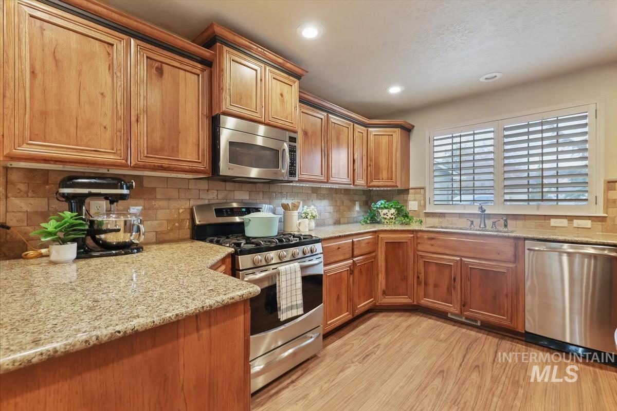 647 North Shadowfox Place Eagle, ID 83616 - Photo 9 of 35 Kitchen with stainless steel appliances, light granite counters, Custom cabinetry, LVP flooring, and recessed lighting
