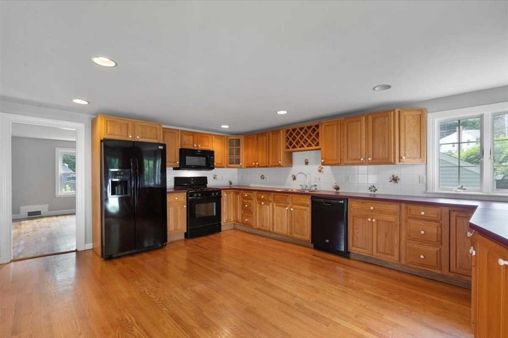 23 Marshall Road Natick, MA 01760 - Photo 9 of 31 a large kitchen with stainless steel appliances granite countertop a refrigerator a sink dishwasher a stove and white cabinets with wooden floor