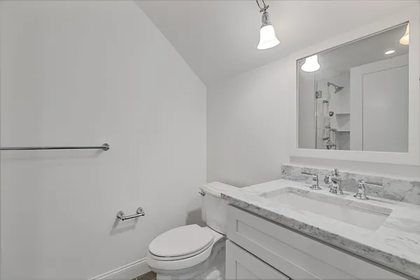 a bathroom with a granite countertop sink a toilet and a mirror