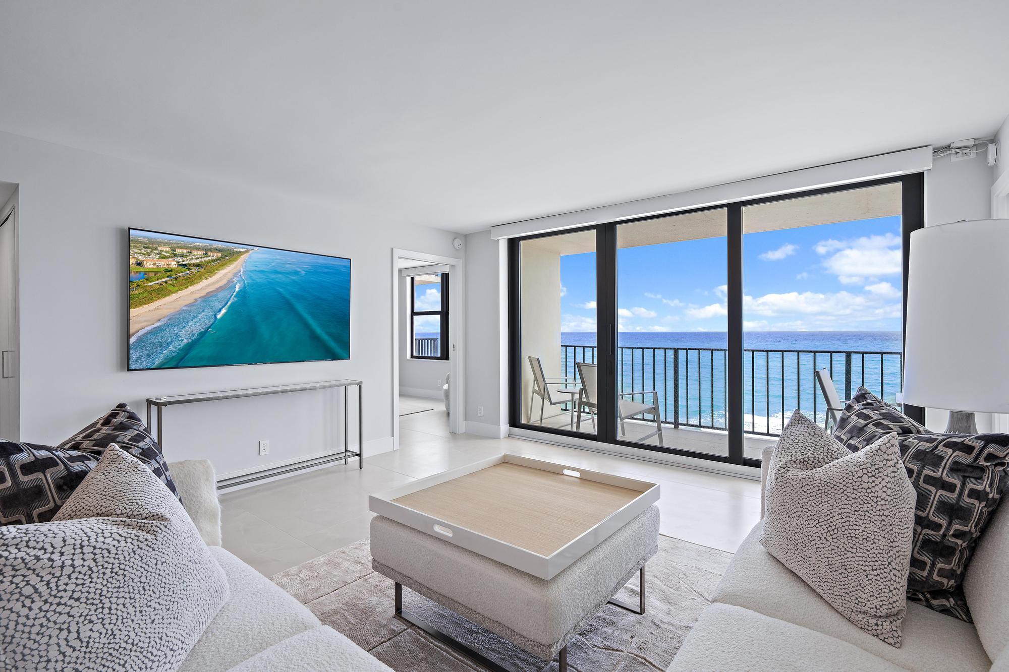 3456 South Ocean Boulevard, Unit 701 Palm Beach, FL 33480 - Photo 2 of 20 a living room with furniture a flat screen tv and a floor to ceiling window