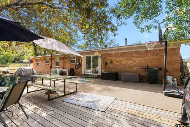 a view of a patio with table and chairs a barbeque with wooden fence and floor