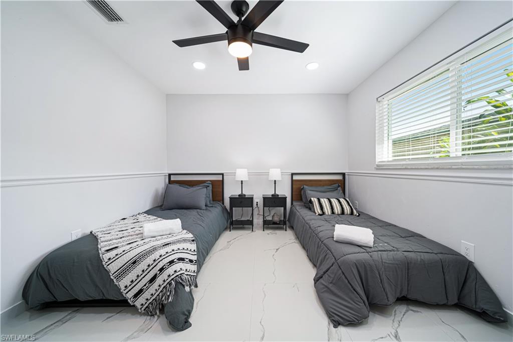 4439 Parrot Avenue Naples, FL 34104 - Photo 21 of 39 a bedroom with two beds and a chandelier