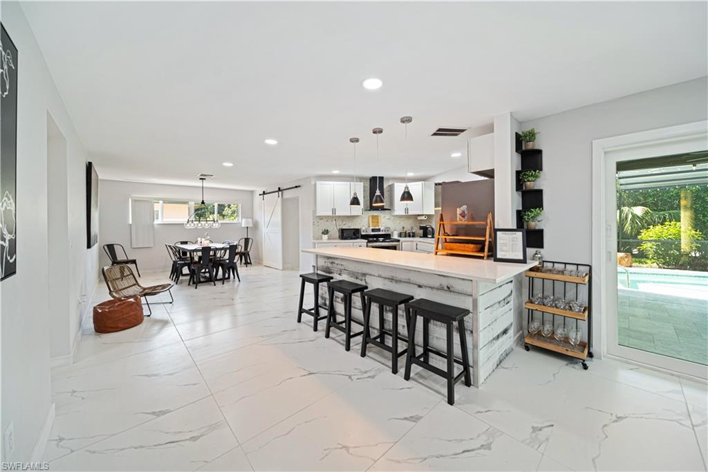 4439 Parrot Avenue Naples, FL 34104 - Photo 6 of 39 a room with stainless steel appliances lots of white furniture a dining table and chairs