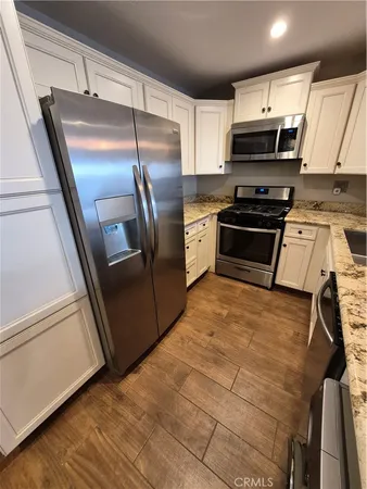 a kitchen with granite countertop a refrigerator and a stove top oven