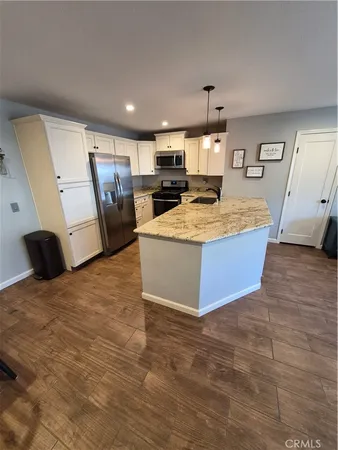 a large kitchen with kitchen island a stove a refrigerator a sink dishwasher and a fireplace with wooden floor