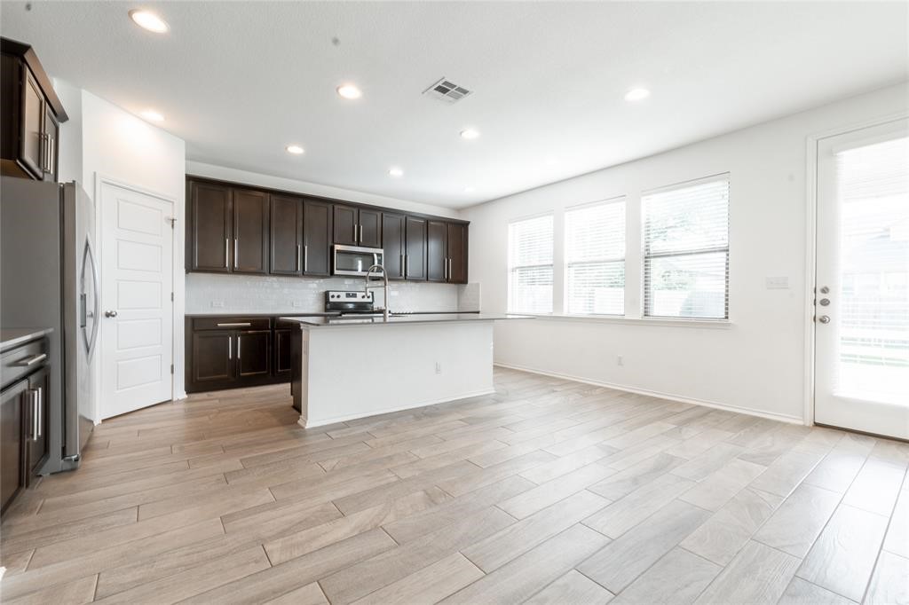 1333 Terrace View Drive Georgetown, TX 78628 - Photo 10 of 35 A well-lit kitchen with dark cabinetry, modern appliances, and a central island.