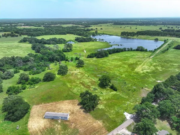 an aerial view of residential houses with outdoor space and trees