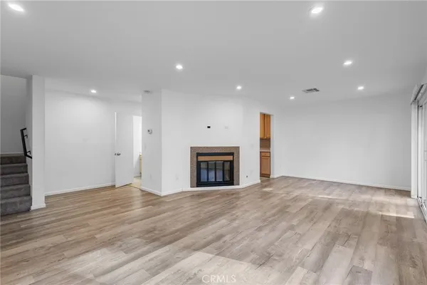 a view of an empty room with wooden floor fireplace and a window