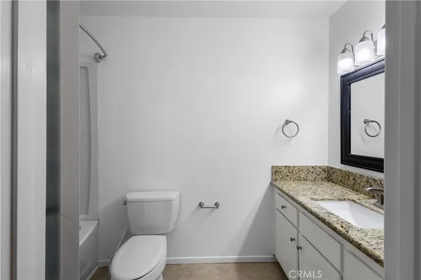 a bathroom with a granite countertop toilet sink and mirror