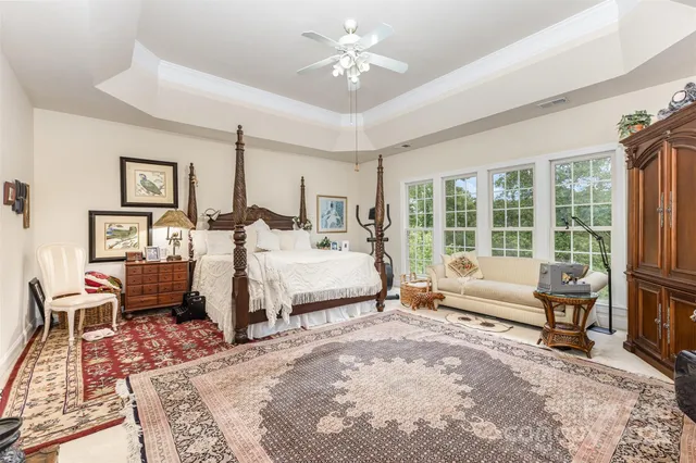 a spacious bedroom with a large bed a chandelier and windows