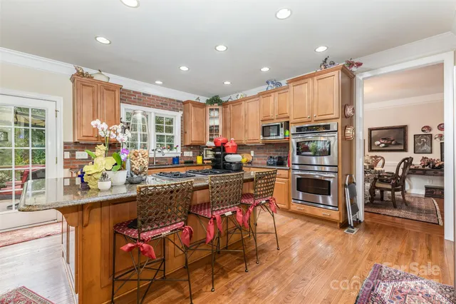 a kitchen with stainless steel appliances kitchen island granite countertop a stove top oven a sink a dining table and chairs
