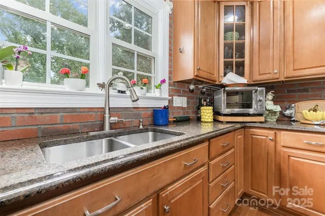 a kitchen with granite countertop a sink and a white wooden cabinets