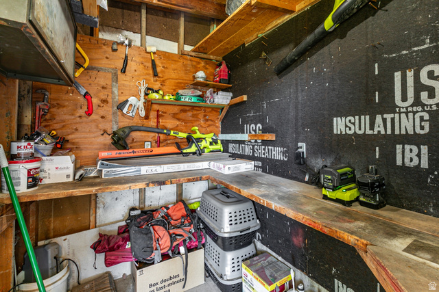 1619 Davis Drive Layton, UT 84041 - Photo 23 of 27 Workshop/Utility room featuring wood paneling, built-in shelving, a built-in workbench, and dark sheathing on one wall