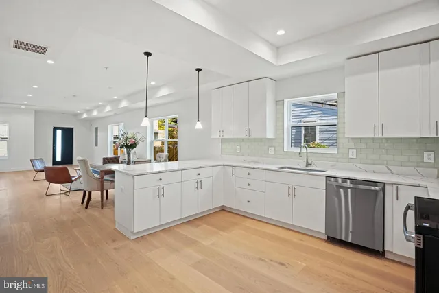 a large white kitchen with a sink table and chairs