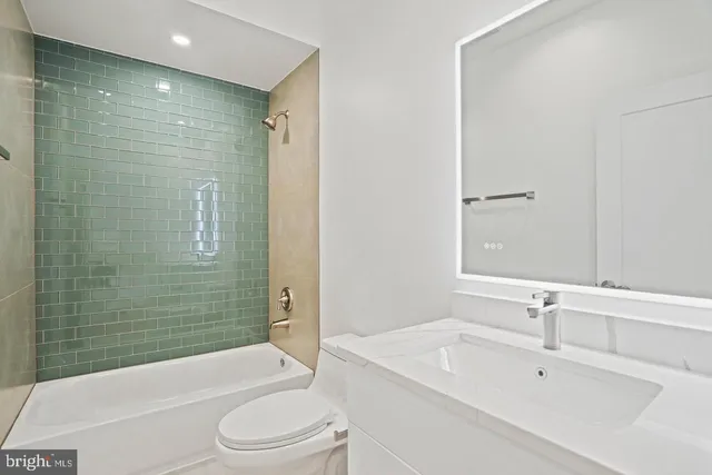 a bathroom with a bathtub shower sink vanity mirror and toilet