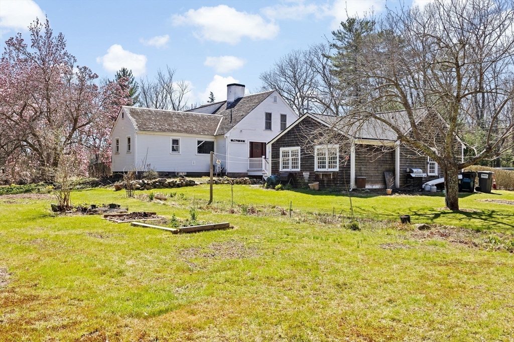 385 Whiting Street Hanover, MA 02339 - Photo 33 of 42 a view of a white house with a large pool and a lawn chairs under an umbrella