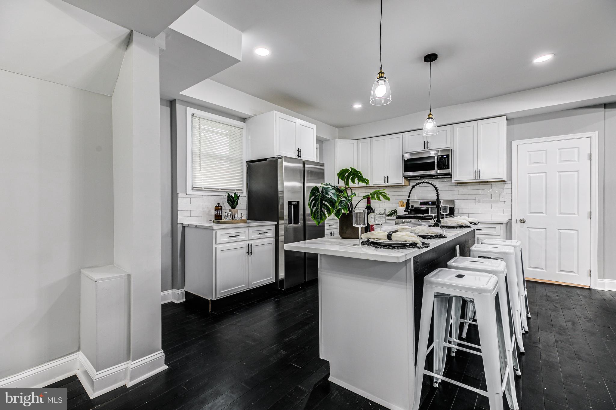 5011 Catalpha Road Baltimore, MD 21214 - Photo 16 of 42 a kitchen with kitchen island white cabinets and stainless steel appliances