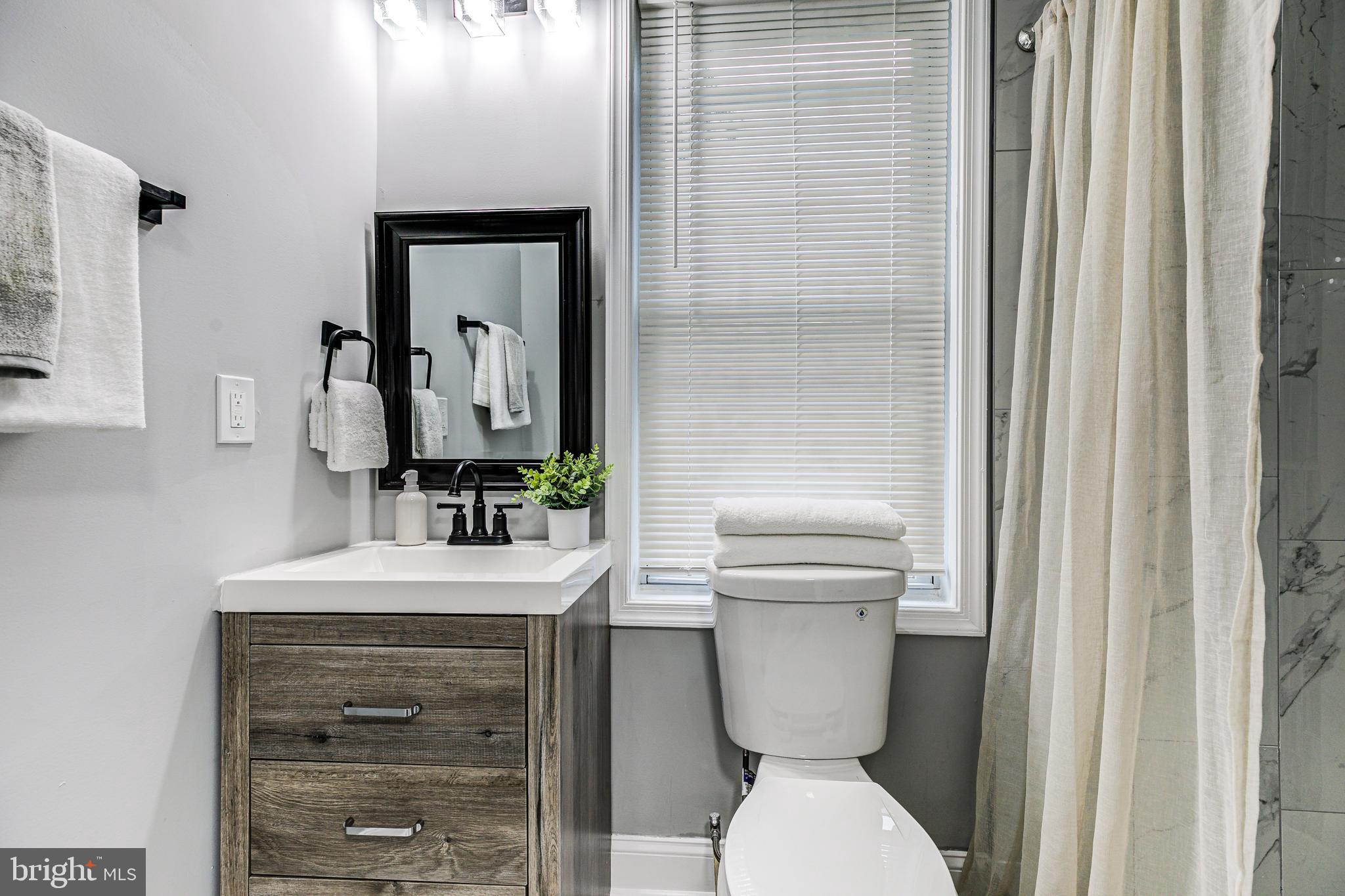 5011 Catalpha Road Baltimore, MD 21214 - Photo 29 of 42 a bathroom with a toilet a sink and mirror