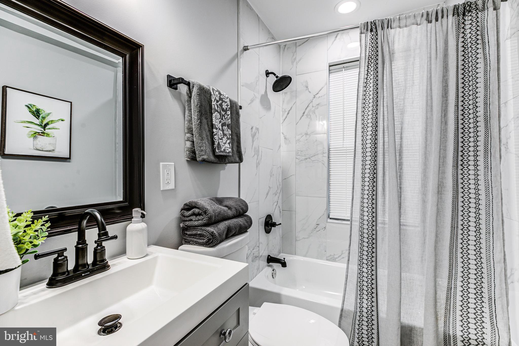 5011 Catalpha Road Baltimore, MD 21214 - Photo 33 of 42 a bathroom with a sink a toilet and shower curtain