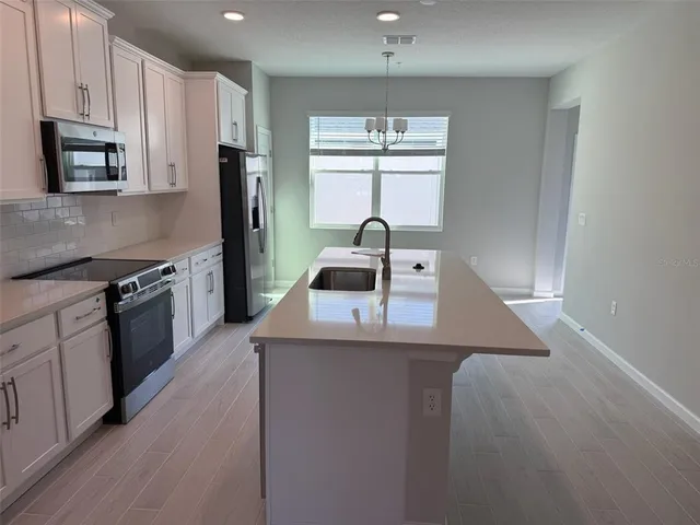 a kitchen with kitchen island granite countertop a sink cabinets and stainless steel appliances